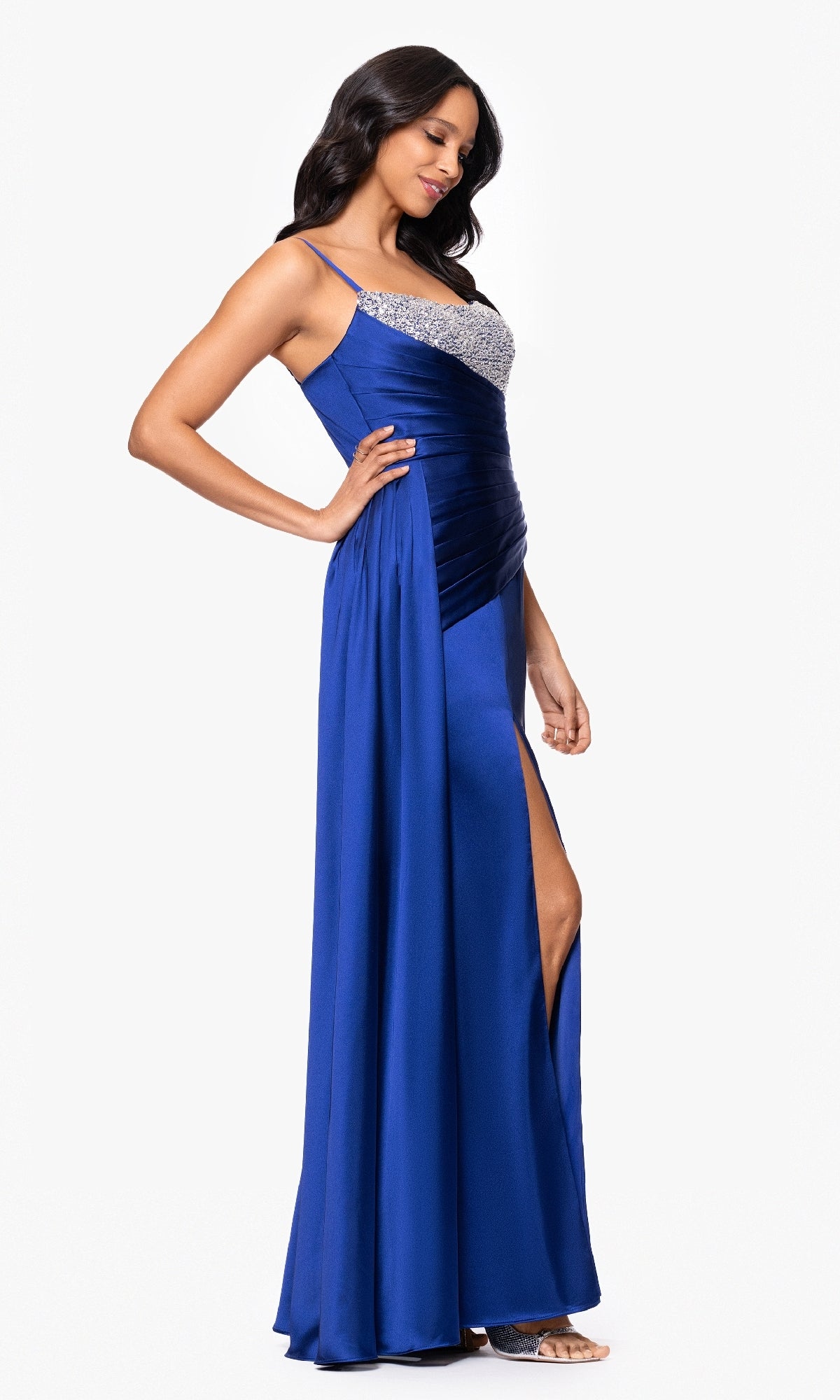 Model wearing the Blondie Nites 5423BN long blue formal dress featuring a thigh-high leg slit and sequin-embellished neckline, posed against a plain white background.